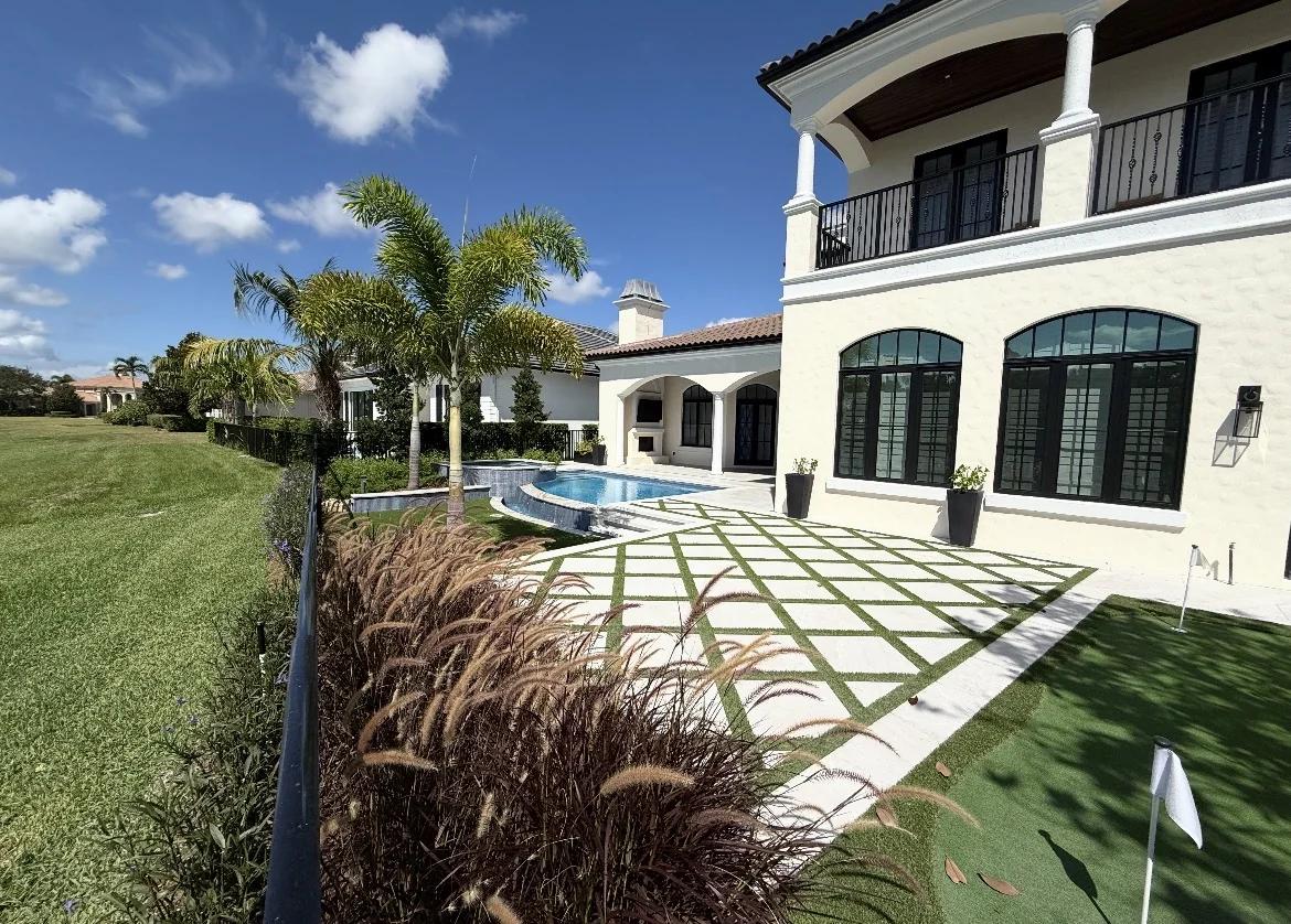 Cream stucco villa backyard with pool, spa, putting green, and a diamond turf-paver patio