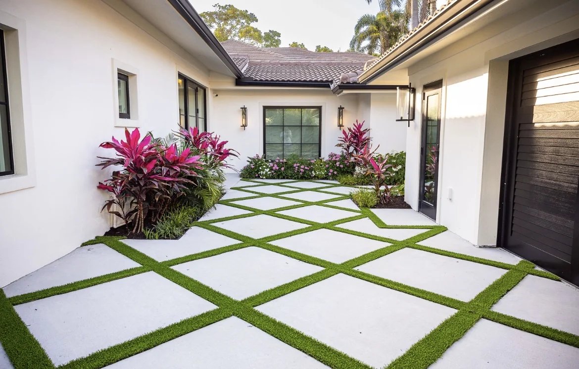 White front courtyard with a diamond paver grid and tropical cordyline accents
