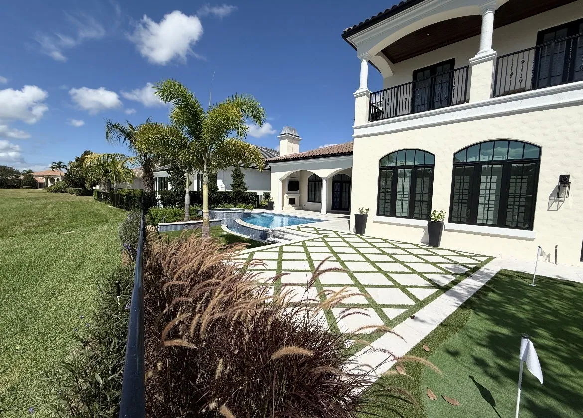 Cream stucco villa backyard with pool, spa, putting green, and a diamond turf-paver patio