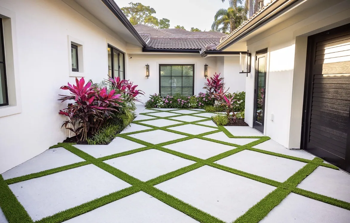 White front courtyard with a diamond paver grid and tropical cordyline accents