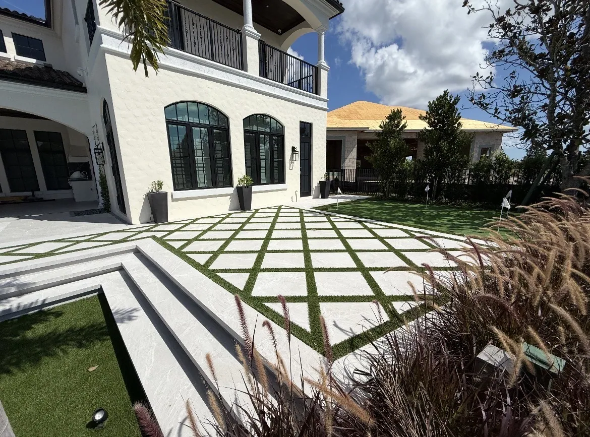 Modern two-story villa with a diamond turf-and-paver patio and ornamental grasses